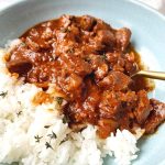 A bowl of beef stew with barbecue sauce and vegetables